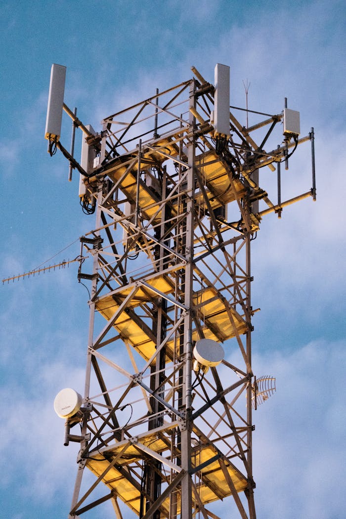 Close-up of a modern telecommunications tower with antennas set against a clear blue sky.
