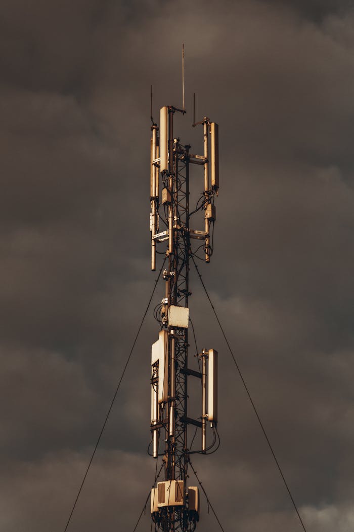 A telecommunications tower stands tall against a backdrop of dark, stormy clouds, exuding a dramatic and moody atmosphere.